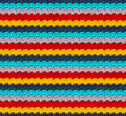 Seamless knitted pattern crocheted from bright acrylic yarn. Pixel style. Ethnic motives.