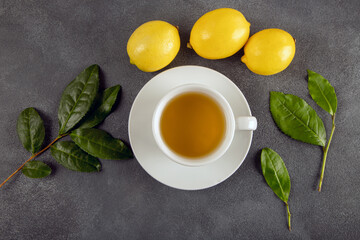 Obraz na płótnie Canvas A cup of green tea, tea leaves and lemons, on dark background 