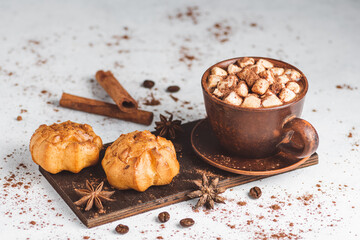 Hot chocolate drink with marshmallows in a cup and sweet bakery eclair dessert sprinkled with cocoa...