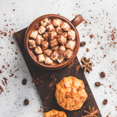 Hot chocolate drink with marshmallows in a cup and sweet bakery eclair dessert sprinkled with cocoa powder, cinnamon stick and star anise, top view