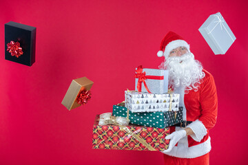 Portrait von einem verkleideten Weihnachtsmann mit Geschenk, isoliert auf roten Hintergrund im...