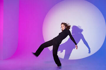 Fototapeta na wymiar Teenage girl dances in a spotlight.