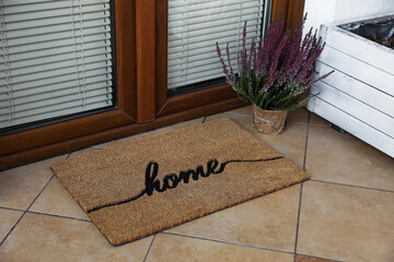 Doormat with word Home and flowers near entrance outdoors