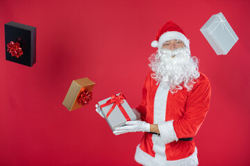 Portrait von einem verkleideten Weihnachtsmann mit Geschenk, isoliert auf roten Hintergrund im...