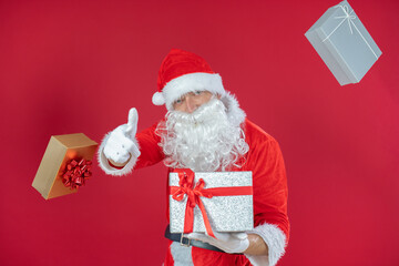 Portrait von einem verkleideten Weihnachtsmann mit Geschenk, isoliert auf roten Hintergrund im...