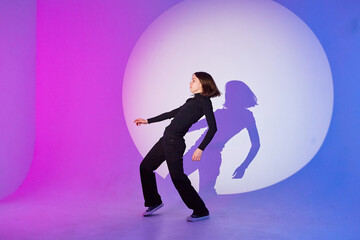 Teenage girl dances in a spotlight.