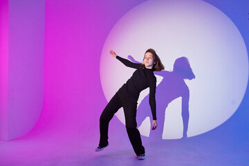 Teenage girl dances in a spotlight.