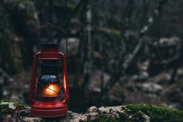 A red kerosene lantern in the autumn forest. Old kerosene lamp.