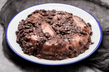 black beans stew with sausages on a white dish