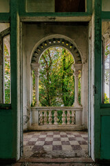 Old overgrown arched balcony in old abandoned mansion