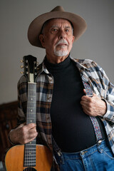 Portrait of senior man with hat and guitar. Blues and country musician
