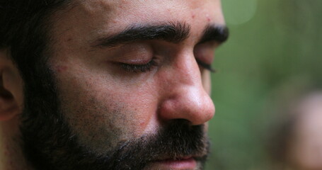 Obraz premium Man meditating outside in nature. Close-up of person face breathing in meditation