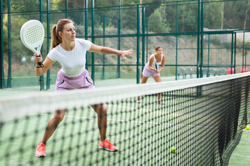 Fototapeta premium Woman in shorts playing padel tennis on court. Racket sport training outdoors.