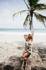 Beautiful girl near the palm tree on the tropical beach