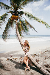 Beautiful girl near the palm tree on the tropical beach