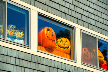 Holloween decorations in window with gray wooden building and white accent paint on holiday in the...