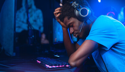 Professional American African gamer upset, tears from losing games of tournaments esport online video, red and blue color background © Parilov
