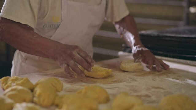 Manos de panadero amasando masa de pan en una panadería.