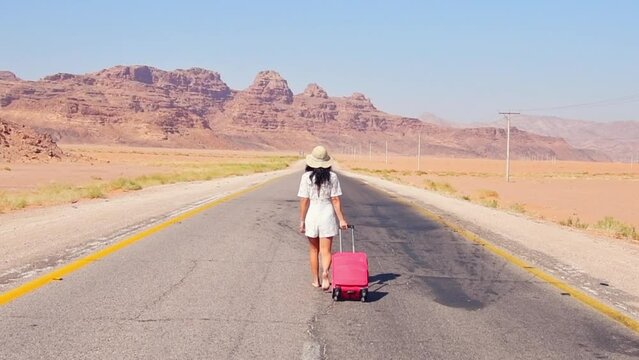 Tourist woman woman walking dragging pink luggage suitcase go travel around world of summer holiday. Lifestyles and travel concept. Travel in Jordan