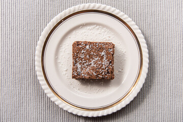 Fototapeta na wymiar brownie with powdered sugar on top on a white dish with golden accents