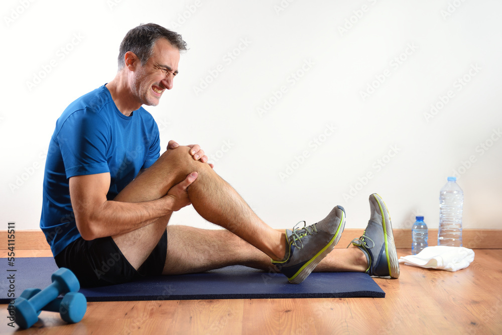 Wall mural Man doing sport indoors complaining with knee pain