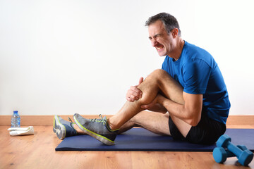 Man doing sport indoors complaining with leg pain