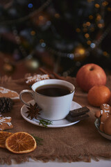 Aesthetics Christmas breakfast - cup of coffee, cookies, tangerines near Christmas tree.