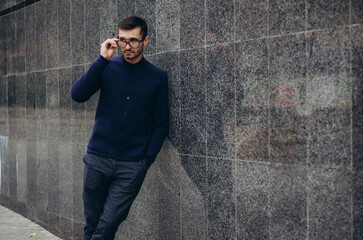 Obraz premium a man with glasses in his hand stands by the wall 