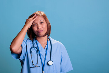 Depressed medical worker suffering from headache after working at health care system expertise. Old depressed physician nurse having migraine during checkup visit appointment