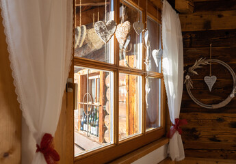 Mountain hut window with white curtains and Christmas decorations on a clear winter day, Austria, Salzburg
