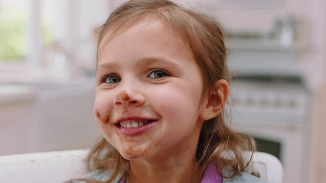 Messy, chocolate and face of girl in kitchen for food, candy and breakfast spread. Happiness, dessert and comic with sweets on mouth of child at home eating for sugar, cake and cocoa snack