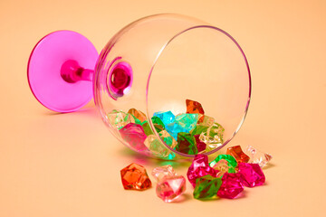 Multi colored gems in wine glass on colorfull background