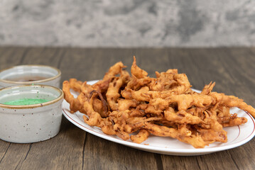 Deep fried crispy appetizer of onion bahji served with humus and dipping sauce