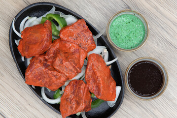 Overhead view of generous portions of lamb boti kabab meat served over a bed of onions and humus dipping sauce for a traditional Indian meal