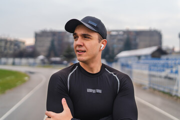 A young man training running stretching jumping a rope on the stadium early in the cold morning 