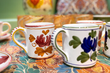 White ceramic plates on a shelf in a store. Designer ceramic plates with a pattern. tableware and eating concept. White jug with roses for table setting with glasses for wine and a bottle for water.