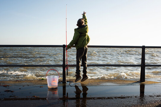 boy fishing for crabs on the quay by the sea