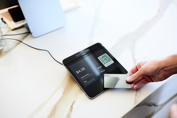 Hand of male customer paying with credit card on modern POS system