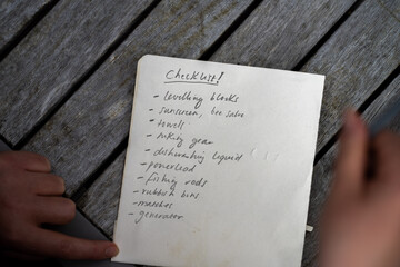 gril writing a camping list in a piece of paper. writing a check list with a pencil