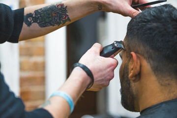 Naklejka premium Close up of barber hands using hair clipper for a male haircut. High quality photo