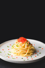 Spaghetti pasta with red caviar on a black background, copy space