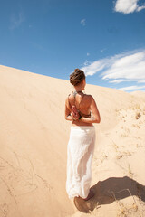 Beautiful natural woman in a sand dune meditating. 