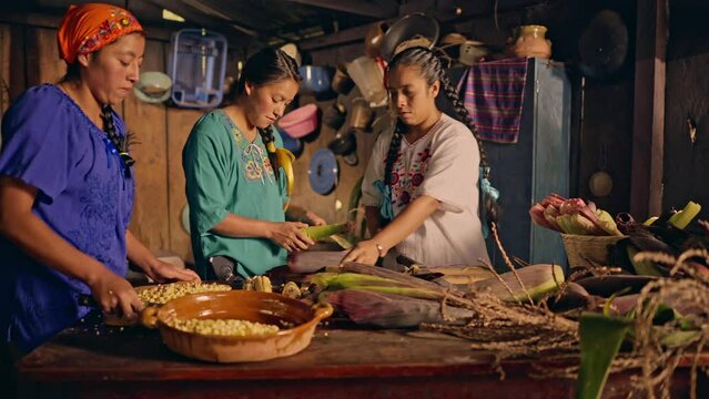 Retrato de Mujeres pelando y cortando elotes frescos para cocinar alimentos en una cocina antigua con estufa de leña.