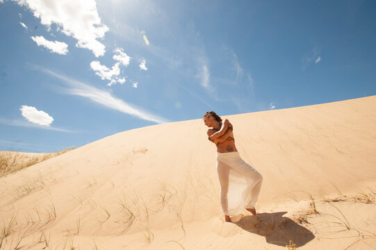 Woman in a landscape of sand dunes and sky.