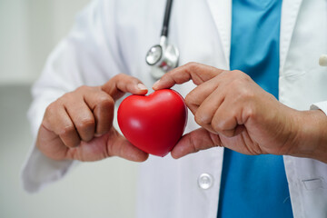 Asian woman doctor holding red heart for health in hospital.