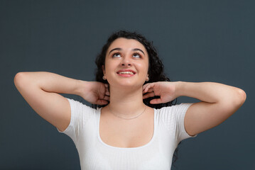 Young beautiful girl smiling happily messing with her hair.