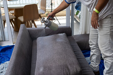 Man pouring a liquid to clean and waterproof sofa cushions.
