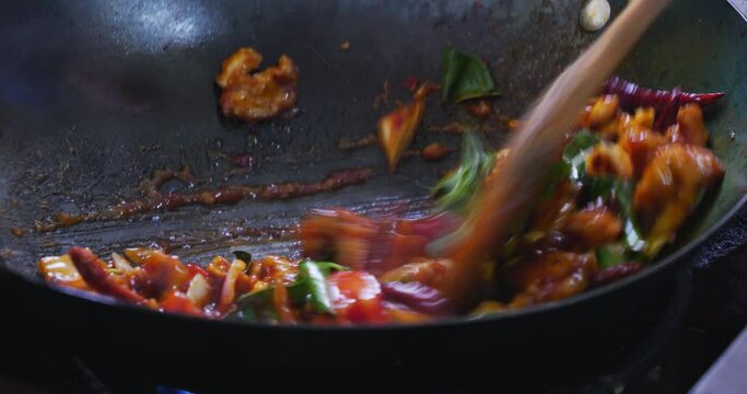 Close-up of a chef putting vegetables on a frying pan ready to serve food.