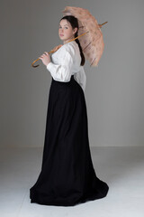 A young Victorian or Edwardian woman wearing a linen Garibaldi blouse and black skirt and holding a vintage parasol
