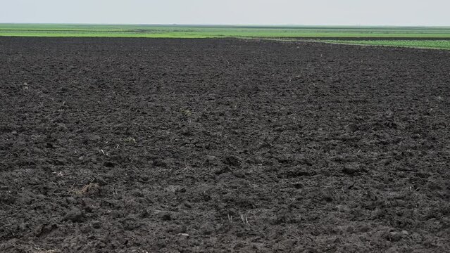 Freshly plowed field ready for seeding and planting. Empty plowed land pin winter. Black soil.